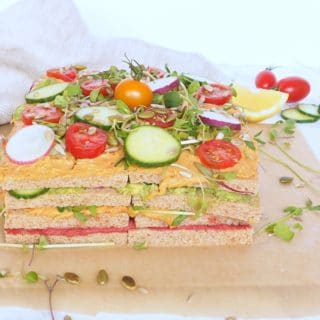 Vegan Sandwich Hummus Cake - Meet the savory hummus sandwich cake, a spin on the classic Swedish sandwich cake, it's made with layers of whole grain bread, hummus, avocado, and veggies. It's a guaranteed scene stealer at your next event and because it requires no cooking, is perfect for hot weather days. Easy to adapt to your favorite fillings and toppings. Let kids make their own version! halsanutrition.com