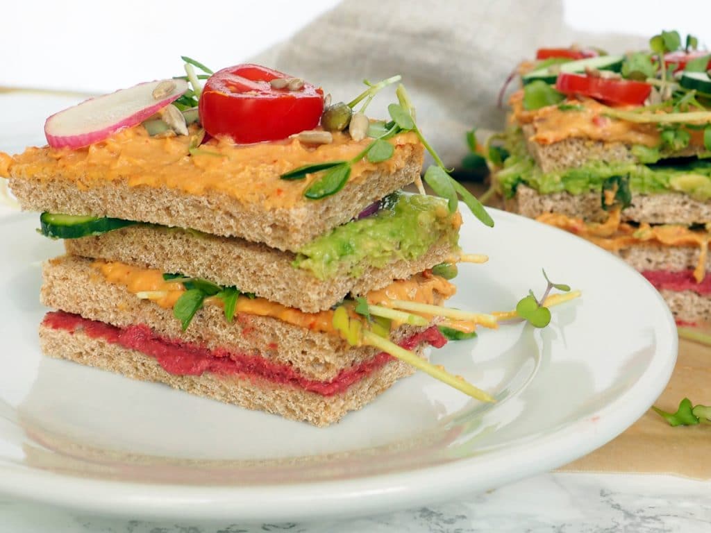 #ad Vegan Sandwich Hummus Cake - Meet the savory hummus sandwich cake, a spin on the classic Swedish sandwich cake, it's made with layers of whole grain bread, hummus, avocado, and veggies. It's a guaranteed scene stealer at your next event and because it requires no cooking, is perfect for hot weather days. Easy to adapt to your favorite fillings and toppings. Let kids make their own version! halsanutrition.com 