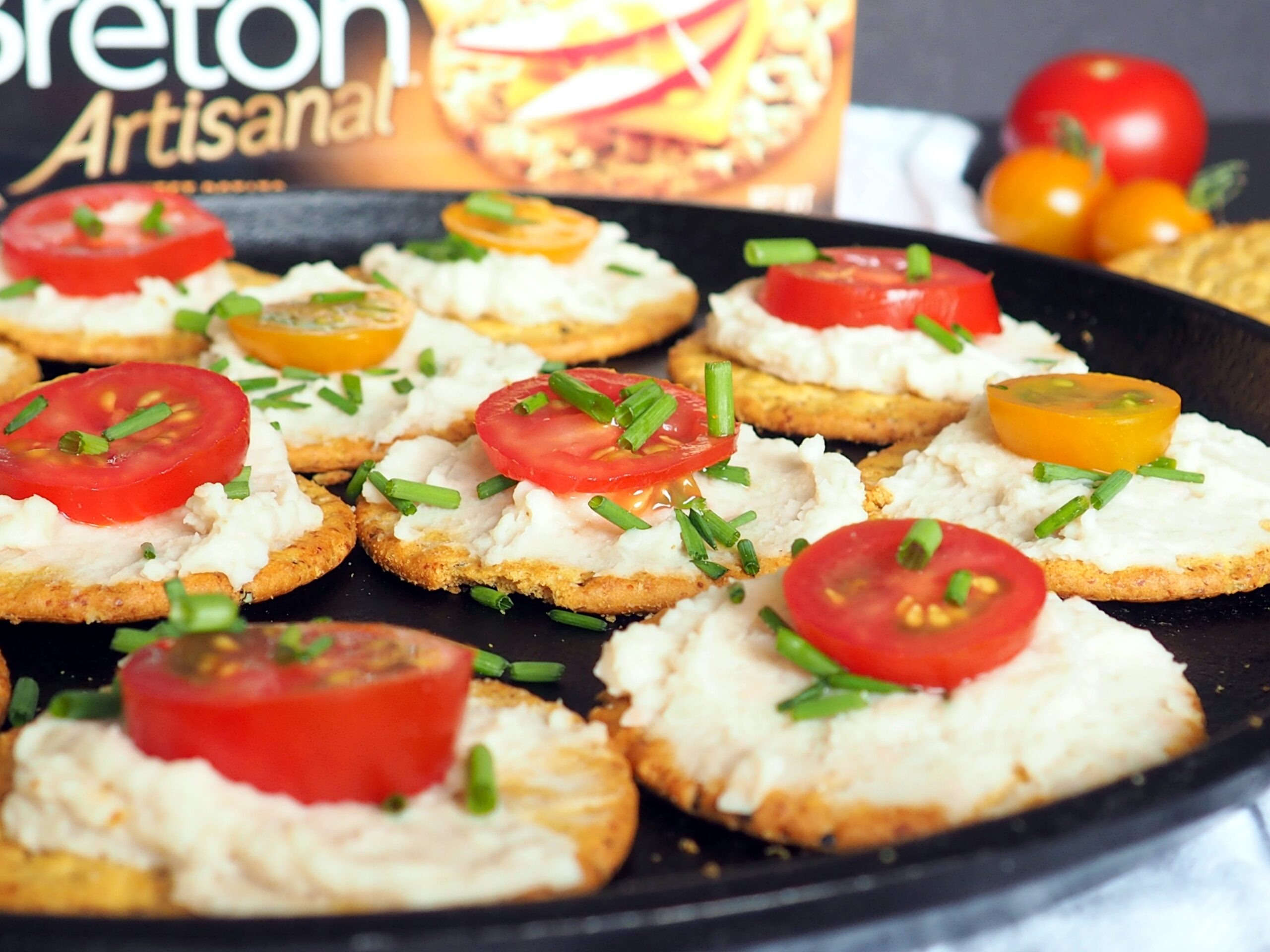 #ad Need a healthy but simple appetizer idea for your next get-together? These crackers with white bean dip, tomatoes, and chives are perfect! Use summer fresh grape or cherry tomatoes for maximum flavor! #vegan From halsanutrition.com