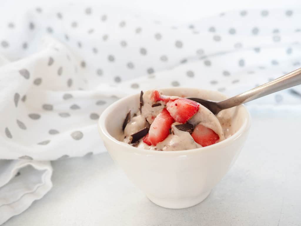 This banana coconut nice cream with dark chocolate and strawberries is vegan and gluten-free. So creamy and delicious, it's a treat the whole family will love! From halsanutrition.com