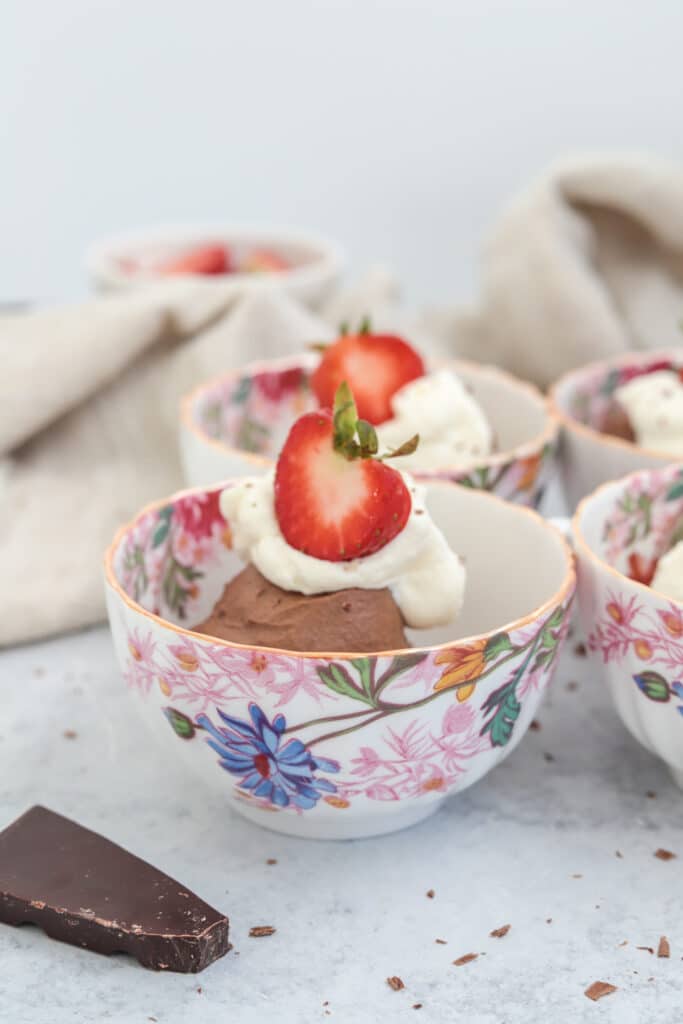 mocha mousse with whipped cream and strawberries in a fancy patterned coffee cup